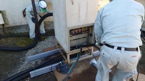 屋外の分電盤へ、地中から立ち上げたケーブルを引き込む作業