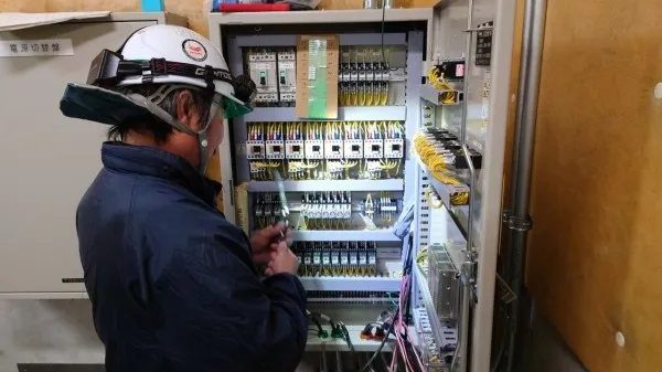 電源切替盤の扉を開け、盤内の機器を調整する作業員